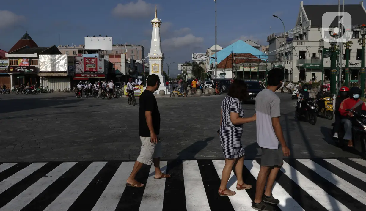 Warga melintas di sekitar perempatan Tugu Pal Putih Yogyakarta, Sabtu (26/12/2020). Proses penataan kawasan Tugu Pal Putih Yogyakarta telah rampung dilakukan, dan kini area yang menjadi salah satu ikon kota Yogya terlihat lebih rapi dan indah tanpa kabel melintang. (Liputan6.com/Helmi Fithriansyah)