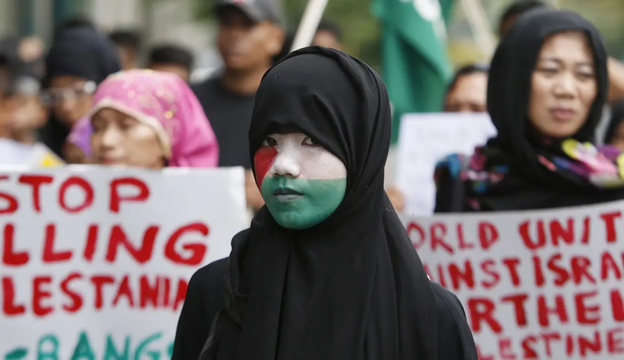 Dalam aksinya, di depan kantor kedutaan Israel di Taguig, Metro Manila, (15/7/2014), salah satu warga muslim Filipina mencat wajahnya dengan gambar bendera Palestina. (REUTERS/Erik De Castro)