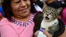 Seorang wanita membawa kucing peliharaannya untuk diberkati di Gereja San Pablo Ermitano, Mexico City, Meksiko (22/1). Santo Anthony dikenal sebagai santo pelindung hewan peliharaan. (AFP Photo/Ronaldo Schemidt)