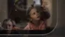 Elina (4) melihat ibunya Lolita dalam kereta menuju Polandia untuk melarikan diri dari perang di stasiun kereta di Lviv, Ukraina, 15 April 2022. Pria Ukraina berusia 18-60 tahun dilarang meninggalkan negaranya dan diminta untuk berperang. (AP Photo/Emilio Morenatti)