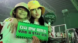 Ibu dan anak satu ini pun tampil kompak dengan kaos putih serta bucket hat. Keduanya juga turut memegang hand banner sebagai penggemar Stray Kids, STAY. (Liputan6.com/IG/@ayutingting92)