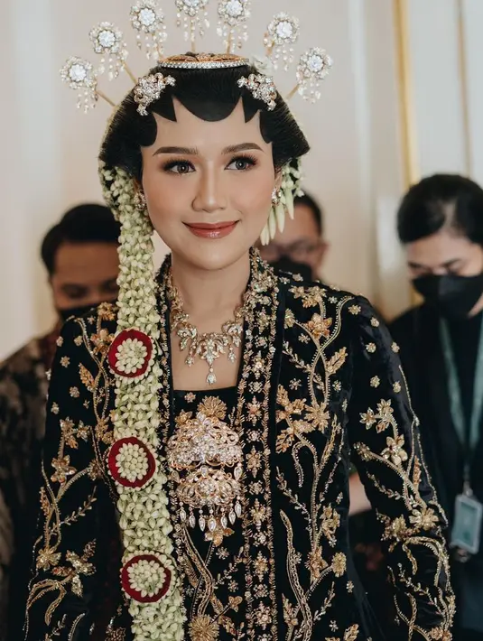 Saat menikah, Erina Gudono tampil dengan kebaya hitam velvet dihiasi bordiran emas. Dipadukan kalung dan bros keemasan pula. [@erinagudono]