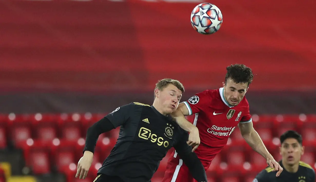 Penyerang Liverpool, Diogo Jota melompat saat berebut bola dengan bek Ajax Amsterdam, Perr Schuurs pada matchday kelima Grup D Liga Champions di Anfield, Selasa (1/12/2020). Curtis Jones mencetak gol satu-satunya yang membawa Liverpool melaju ke babak 16 besar. (Peter Byrne/Pool via AP)