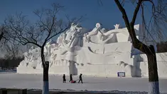 Orang-orang berjalan di samping patung salju raksasa di Pameran Seni Patung Salju Internasional Harbin Sun Island menjelang Festival Es dan Salju Internasional Harbin Tiongkok ke-39 di Harbin, di provinsi Heilongjiang timur laut China (4/1/2023). (AFP/Hector Retamal)