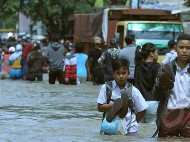 Pelajar berusaha melintasi genangan air ketika banjir merendam Jalan KH Hasyim Ashari, Ciledug, Kota Tangerang, Selasa (10/2/2015). (Liputan6.com/Andrian M Tunay)