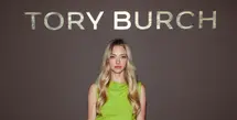 Amanda Seyfried hadir dengan koleksi Resort 2027. Padanan brushed wool top, patent leather skirt, woven raffia belt, dengan the suede Bunny Knot shoulder bag, dan peep-toe pumps. / Foto: Tory Burch.