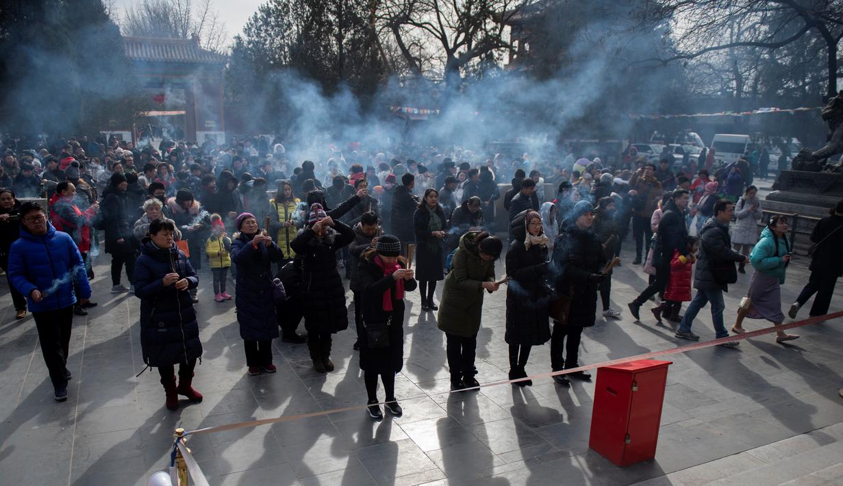 Sejumlah warga berdoa untuk keberuntungan pada hari kelima Tahun Baru Imlek di Yonghegong, atau Kuil Lama di Beijing (9/2). Warga China di seluruh dunia menyambut Tahun Babi pada 5 Februari.  (AFP Photo/Nicolas Asfouri)