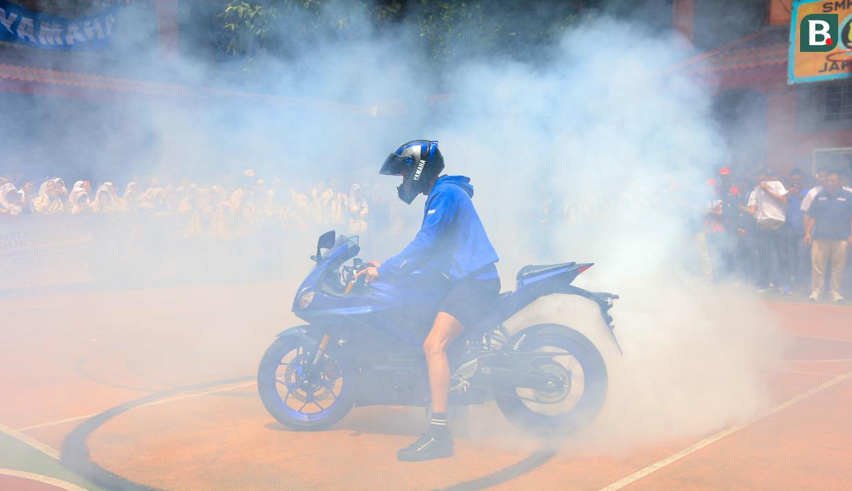 Pembalap asal Turki itu melakukan aksi freestyle dengan teknik wheelie dan donuts. Aksi donuts yang dilakukan Toprak Razgatlioglu sampai membuat SMK Negeri 39 Jakarta menjadi kepulan asap. (Bola.com/M Iqbal Ichsan)