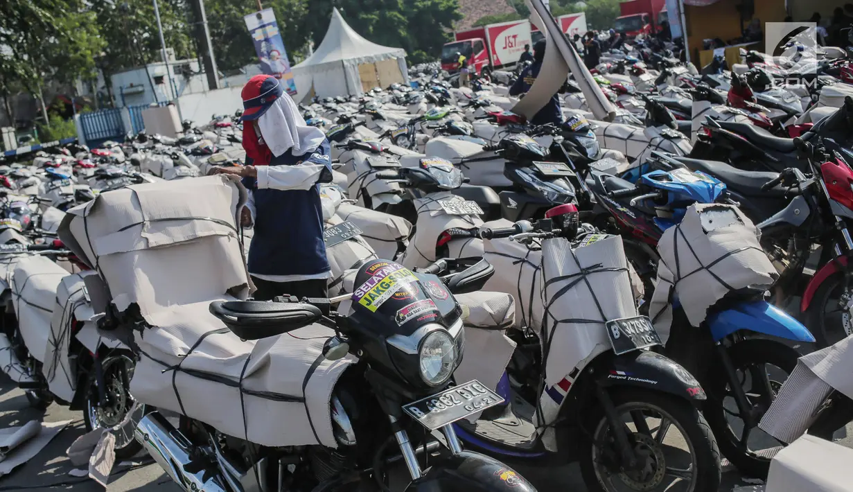 Pekerja membungkus motor pemudik sebelum dikirim dengan kereta api di Stasiun Jakarta Gudang, Selasa (28/5/2019). Direktorat Lalu Lintas dan Angkutan Kereta Api Kementerian Perhubungan mengangkut 18.096 motor pemudik secara gratis pada mudik Lebaran 2019. (Liputan6.com/Faizal Fanani)