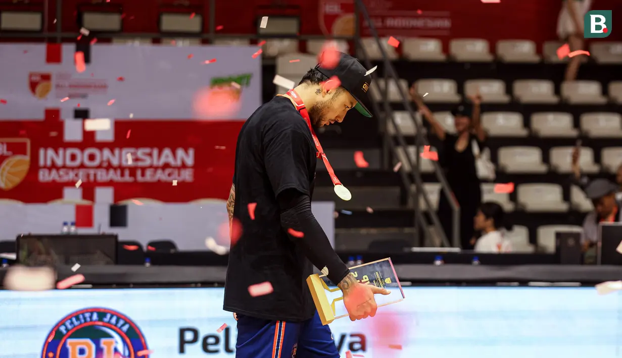 Pemain Pelita Jaya, Brandon Jawato berjalan menuju area wawancara setelah menerima penghargaan pemain terbaik atau MVP pada final ketiga final IBL All Indonesia 2024 melawan Satria Muda yang berlangsung di Hall Basket, Senayan, Jakarta, Sabtu (06/10/2024). (Bola.com/Bagaskara Lazuardi)