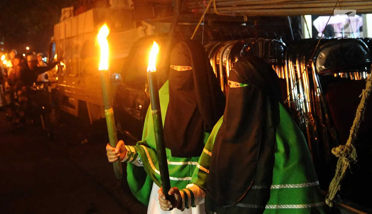 Dua wanita membawa obor saat melakukan aksi longmarch sejuta obor dari kawasan Sukasari menuju Ciawi, di Jalan Raya Tajur, Bogor, Senin (10/9). Aksi ini dilakukan dalam rangka memperingati Tahun Baru Islam 1440 H. (Merdeka.com/Arie Basuki)