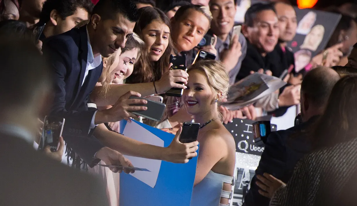 Jennifer Lawrence menyapa para fans saat menghadiri penayangan perdana film terbarunya, "Passengers" di Los Angeles, California, AS, (14/12). Bergaun putih  Jennifer Lawrence tampil cantik dan seksi. (AFP Photo/Valerie Macon)