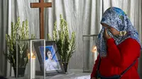 Seorang ibu mengusap air mata di depan peti mati korban bom Surabaya Sri Puji, Surabaya, Jawa Timur, Senin (14/5). Sri Puji menjadi korban meninggal dalam serangan di Gereja Pantekosta. (AFP PHOTO/JUNI KRISWANTO)