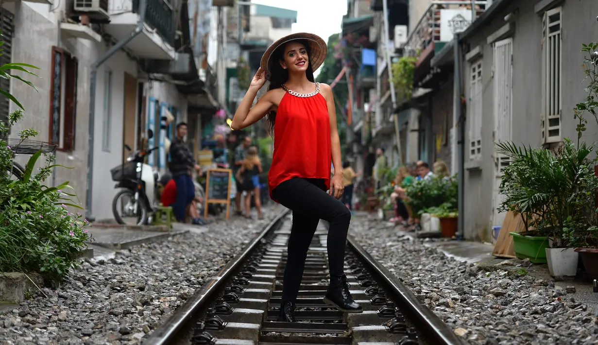 Gambar pada 21 Oktober 2018, turis berfoto di tengah jalur kereta api yang melintasi kawasan permukiman di Hanoi, 20 Oktober 2018. Beberapa tahun terakhir, pengunjung ke kawasan ini lebih menyukai mengambil kesempatan untuk fotografi. (Nhac NGUYEN/AFP)