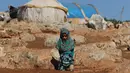 Maya Mohammad Ali Merhi (8) berpose menggunakan kaki prostetik dari kaleng di sebuah kamp orang terlantar di Provinsi Idlib, Suriah, Rabu (20/6). (Aaref Watad/AFP)