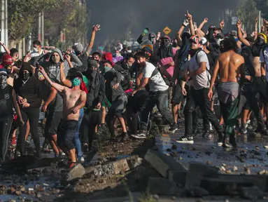Demonstran saat bentrok dengan polisi di tengah pandemi virus corona Covid-19 selama penguncian wilayah (lockdown) di lingkungan miskin di Santiago, Chili, (18/5/2020). Mereka  protes menuntut bantuan makanan dari pemerintah. (AP Photo/Esteban Felix)