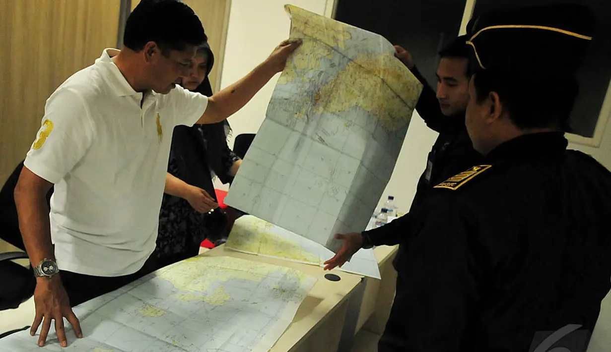 Petugas menunjukkan peta rute Surabaya menuju Singapura yang kemungkinan dilewati pesawat AirAsia QZ 8501 kepada salah satu kerabat penumpang pesawat tersebut, Surabaya, Minggu (28/12/2014). (Liputan6.com/Johan Tallo) 