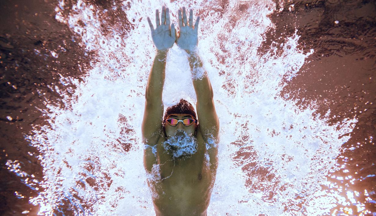 Perenang Indonesia, Muhammad Dwiky Raharjo berkompetisi dalam cabang olahraga renang 100 meter nomor gaya dada putra pada Kejuaraan Akuatik Dunia di Aspire Dome, Doha, Qatar, 11 Februari 2024. (AFP/Oli Scarff)