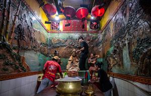 Para sukarelawan membersihkan patung-patung dewa di Kuil Hong San Ko Tee, Surabaya, Jawa Timur, pada Rabu 11 Februari 2026. (JUNI KRISWANTO/AFP)