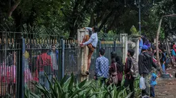 Tampak seorang warga saat memanjat pagar dikawasan Monas untuk menyaksikan Konser Drug Free Asia Africa, Jakarta, Minggu (19/4/2015). Aksi nekat warga ini ditengarai oleh petugas yang menutup akses masuk pengunjung Monas. (Liputan6.com/Faizal Fanani)