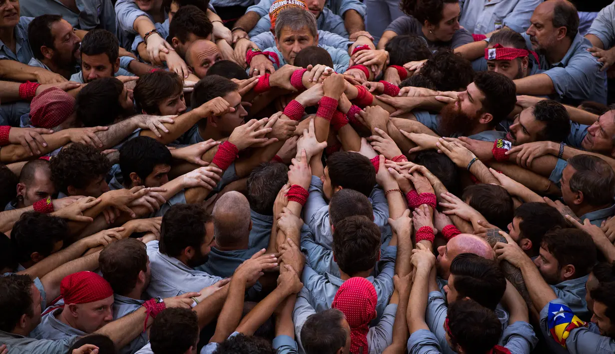 Para Castellers membentuk fondasi untuk menara manusia atau ‘Castell’ di alun-alun Sant Jaume, Barcelona, Spanyol, Minggu (24/9). Ribuan orang separatis Catalonia mendukung referendum kemerdekaan bagian timur Spanyol tersebut. (AP Photo/Emilio Morenatti)