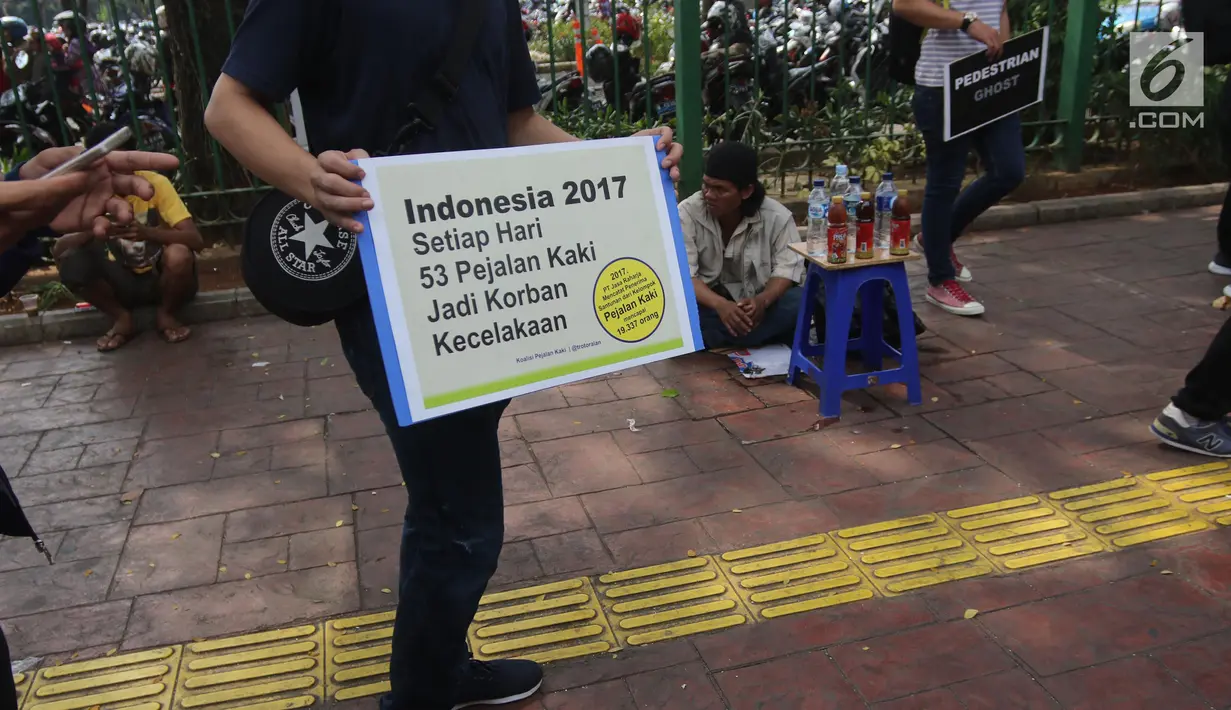 Koalisi Pejalan Kaki menunjukkan poster yang berisi imbauan saat melakukan aksi Tamasya Trotoar Kita di Jalan Medan Merdeka Selatan, Jakarta, Minggu (24/6). (Liputan6.com/Arya Manggala)