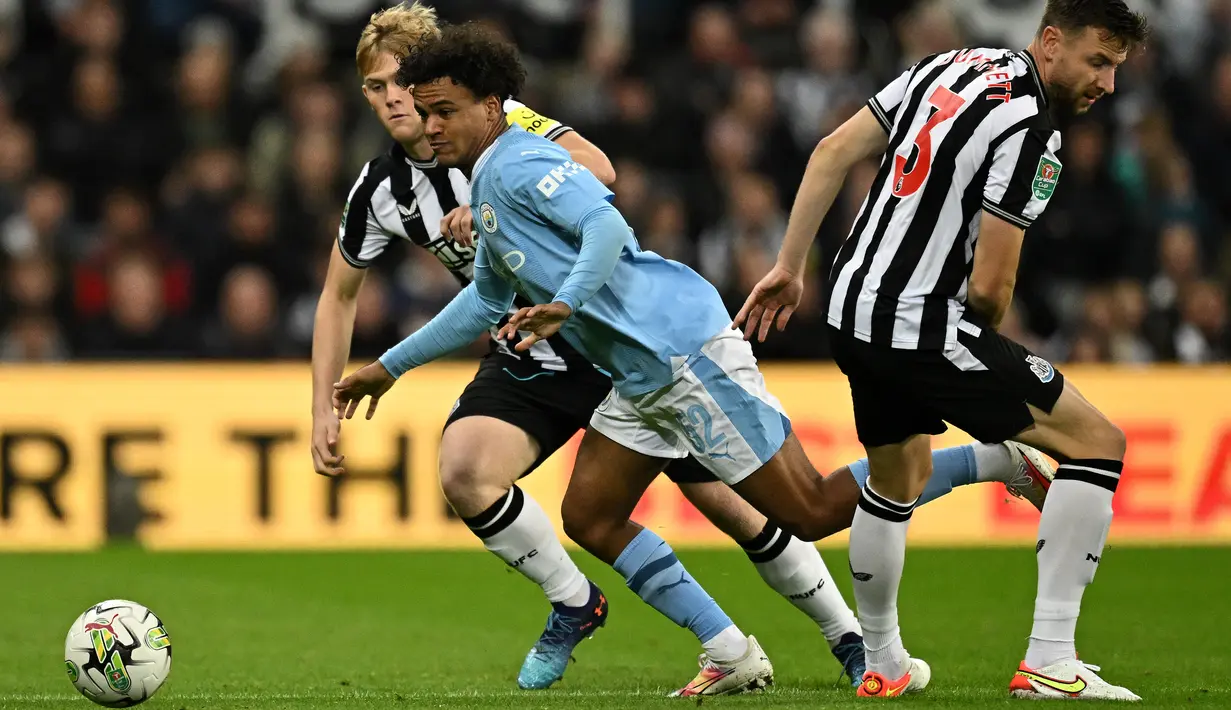 Bek Newcastle United #03 Paul Dummett (kanan) bersaing dengan gelandang Manchester City #52 Oscar Bobb (tengah) dalam laga putaran ketiga Carabao Cup 2023/2024, di St. James' Park, Kamis (28/9/2023). (Oli SCARFF / AFP)