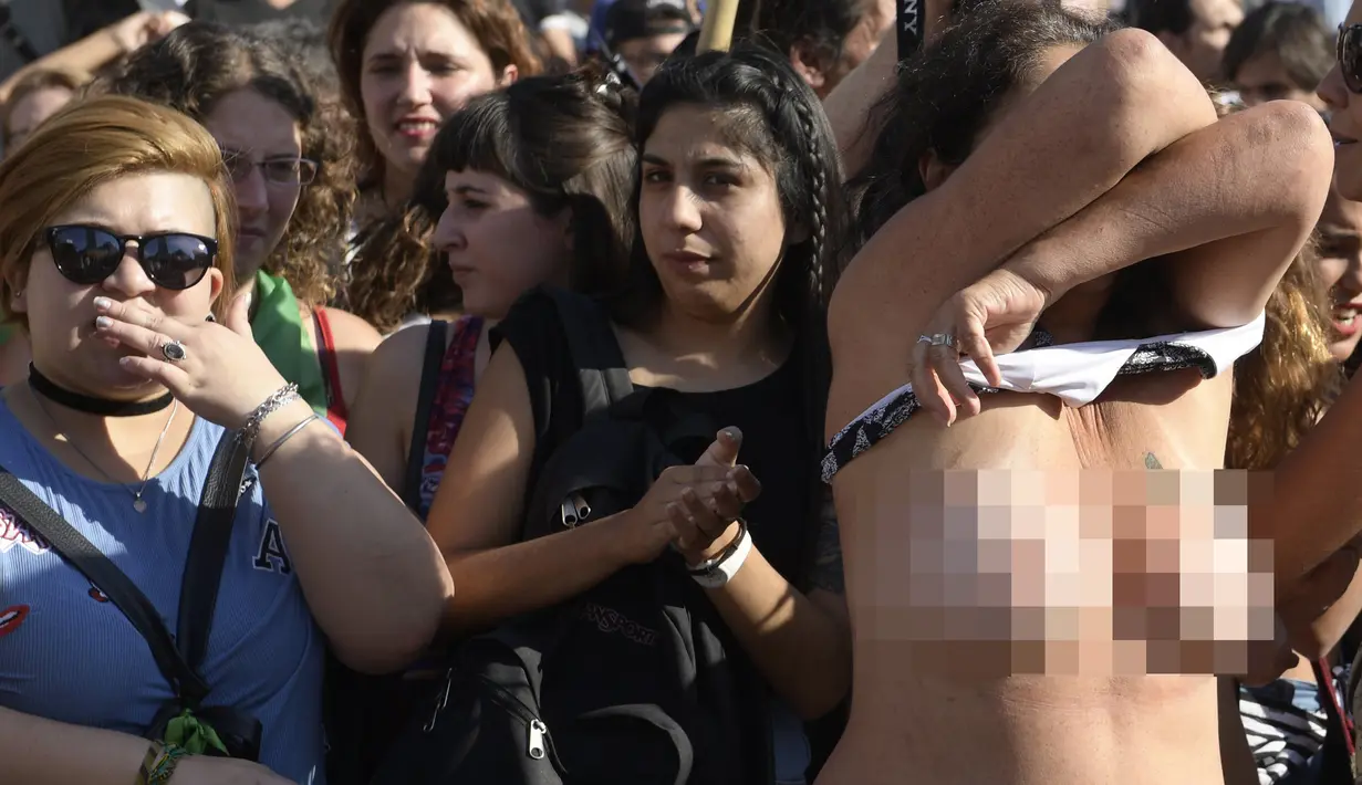 Pengunjuk rasa melepas kausnya saat berpartisipasi dalam unjuk rasa di Ibu Kota Argentina, Buenos Aires, Selasa (7/1). Aksi itu sebagai bentuk protes atas kekerasan yang dilakukan aparat kepolisian terhadap perempuan tanpa bra. (AFP PHOTO/Juan MABROMATA)