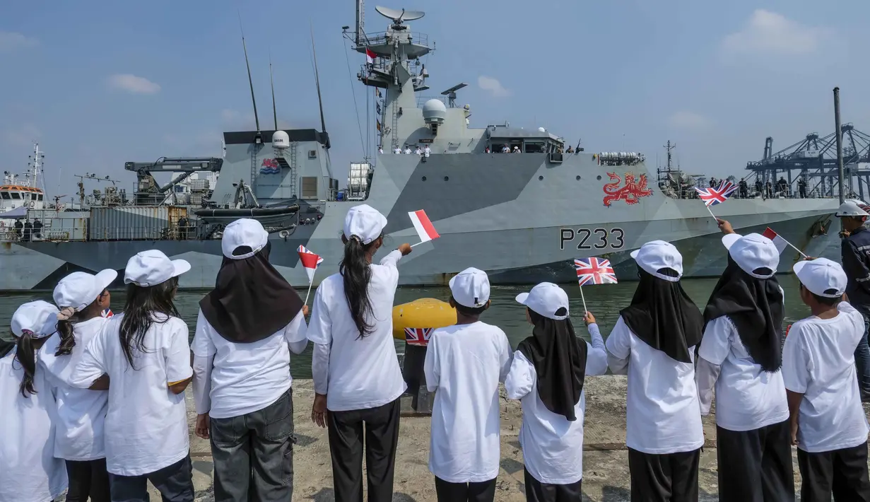 Anak-anak sekolah dasar mengibarkan bendera Indonesia dan Inggris saat menyambut kedatangan Kapal Perang Kerajaan Inggris His Majesty’s Ship (HMS) Tamar di Pelabuhan Tanjung Priok, Jakarta pada Rabu 17 Juni 2026. (BAY ISMOYO/AFP)