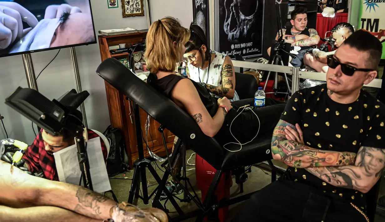 Seniman saat menato sejumlah pencinta tato selama Expotattoo Colombia 2019 di Medellin, departemen Antioquia (2/6/2019). Para penggila tato antusias untuk mentato tubuhnya di festival tato terbesar di negara tersebut. (AFP Photo/Joaquim Sarmiento)
