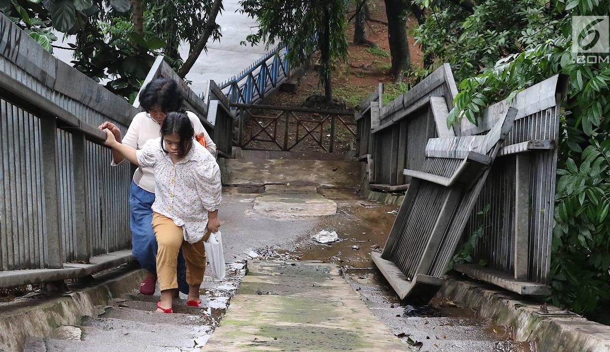 Pejalan kaki menaiki tangga JPO yang rusak di Terminal Kampung Rambutan, Jakarta, Senin (28/1). Kondisi JPO yang sebagian pagar pembatasnya rusak tersebut membahayakan pejalan kaki apabila tidak segera diperbaiki. (Liputan6.com/Immanuel Antonius)