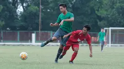 Bek Timnas Indonesia U-16 (kiri) berebut bola dengan pemain Top Skor U-16 pada laga uji coba di Lapangan Atang Sutresna, Cijantung, Kamis (10/5/2018). Tim Top Skor U-16 menang 2-0 atas Timnas Indonesia U-16. (Bola.com/Nick Hanoatubun)