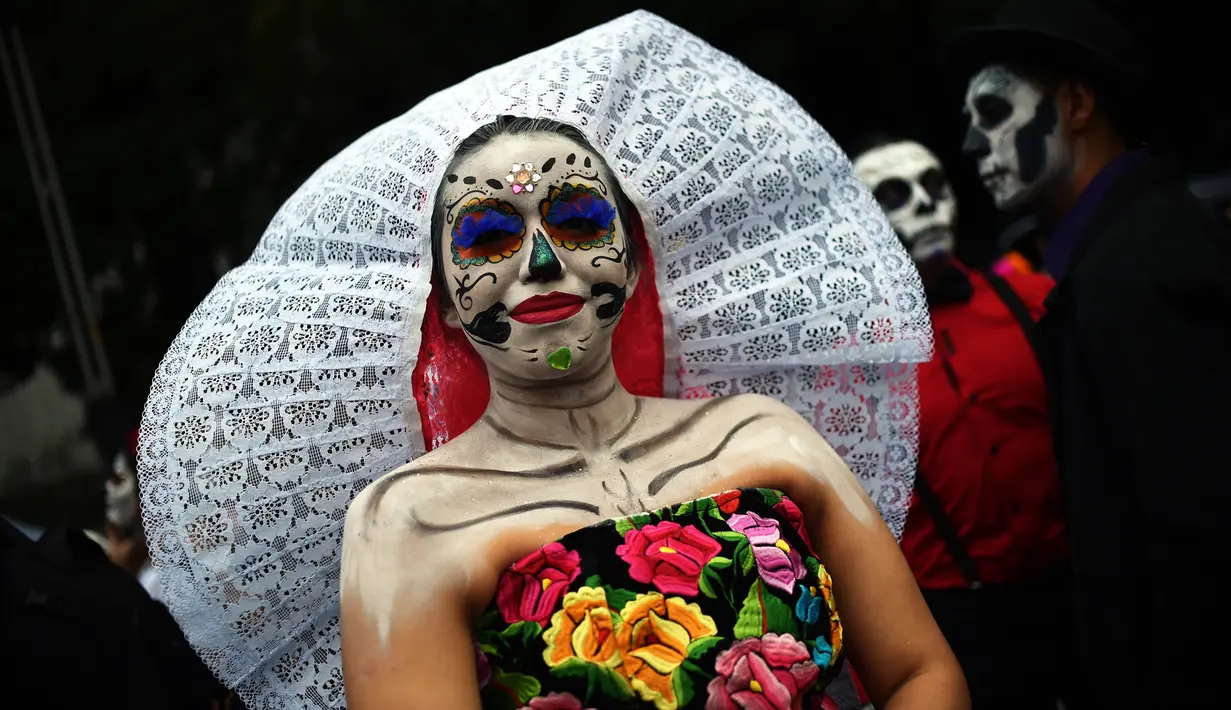 Seorang wanita berpakaian seperti "Catrina" ambil bagian dalam parade Hari Orang Mati di Reforma Avenue, Mexico City, 21 Oktober 2018. Hari kematian ini jadi hari libur nasional di negara-negara Amerika Latin, khususnya Meksiko. (RODRIGO ARANGUA/AFP)