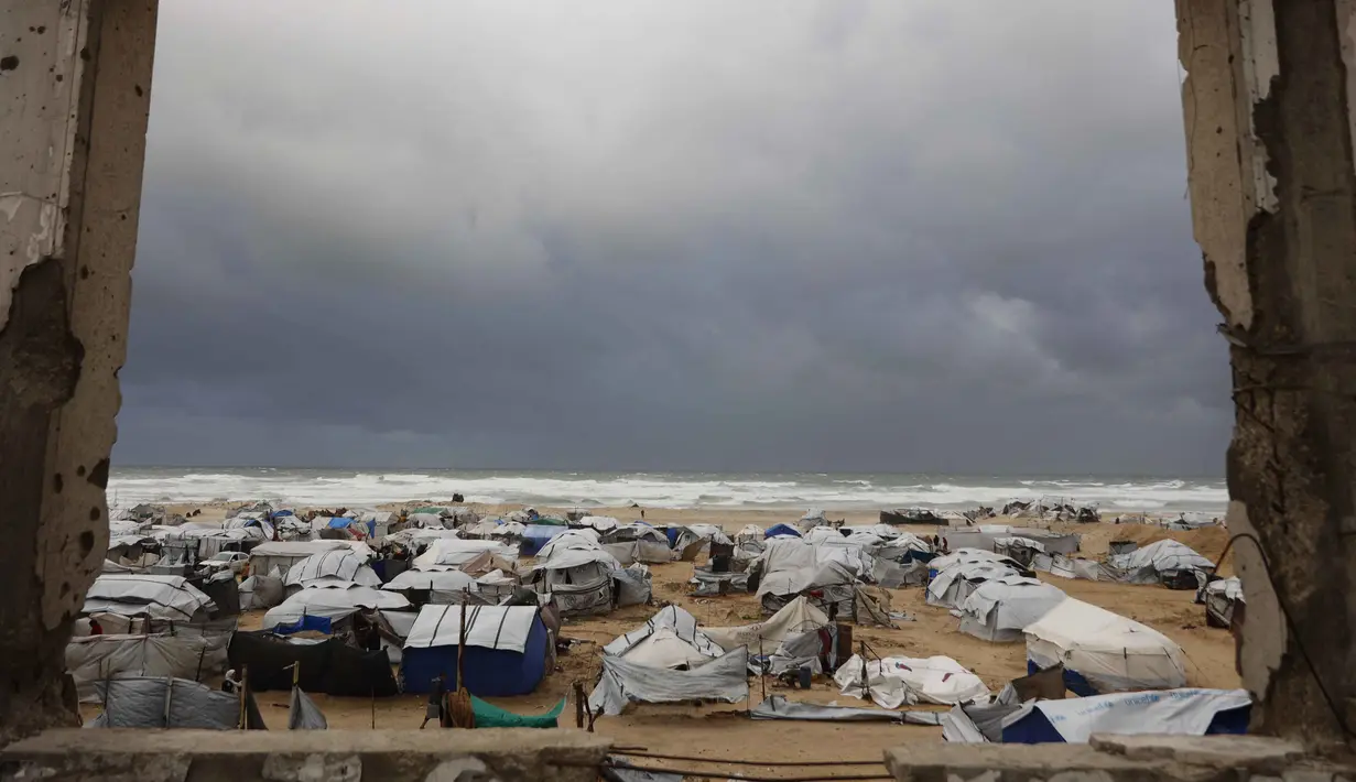 Badai musim dingin yang membawa angin kencang dan suhu ekstrem dilaporkan menghancurkan sejumlah tempat perlindungan. Tampak dalam foto, sebuah foto menunjukkan tenda-tenda penampungan keluarga-keluarga Palestina yang mengungsi, didirikan di sepanjang pantai Kota Gaza saat angin musim dingin yang kencang menerpa wilayah tersebut pada Selasa 13 Januari 2026. (Omar AL-QATTAA/AFP)