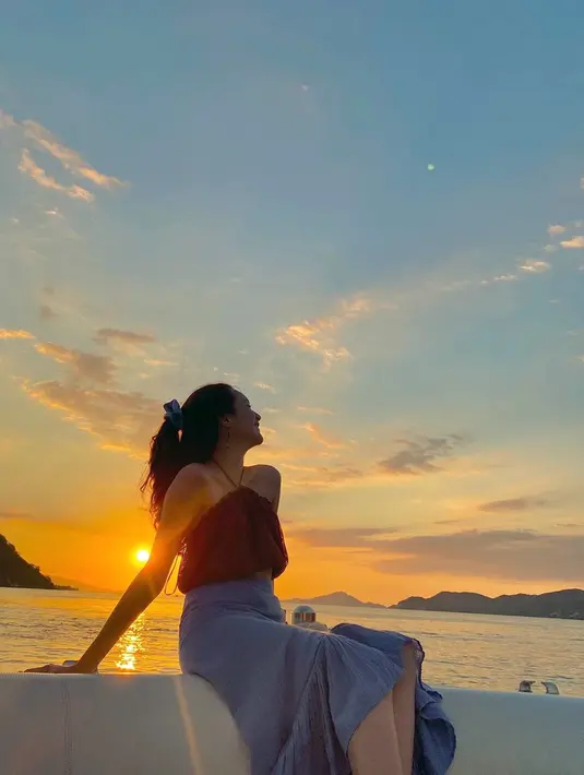 Dalam liburan kali ini pun momen menikmati matahari tenggelam di pinggir pantai jadi indah. Dengan warna langit memancarkan warna jingga, Beby Tsabina pun terlihat memesona saat berfoto dengan latar belakang tersebut. (Liputan6.com/IG/@bebytsabina)