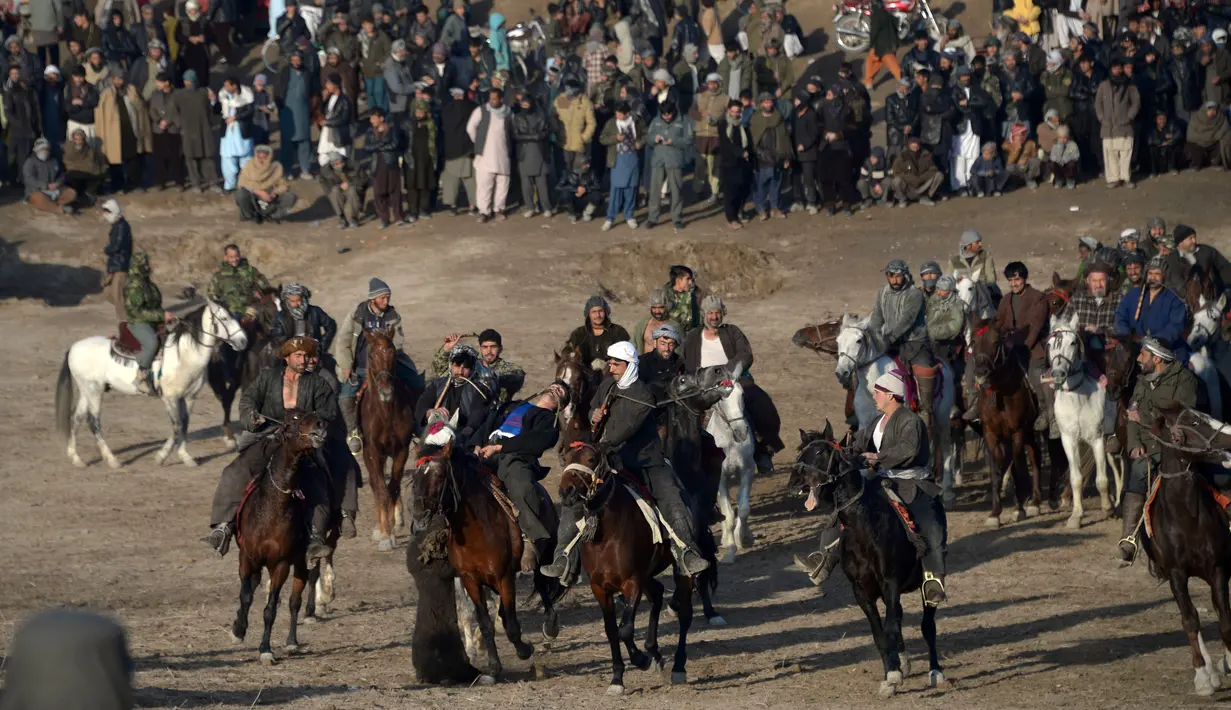 Seorang peserta membawa bangkai yang diperebutkan peserta lainnya saat pertandingan Buzkashi di Mazar-i-Sharif, Afghanistan (20/12). Pemain harus membawa bangkai di sekitar bendera atau penanda di salah satu ujung lapangan. (AFP/Farshad Usyan)