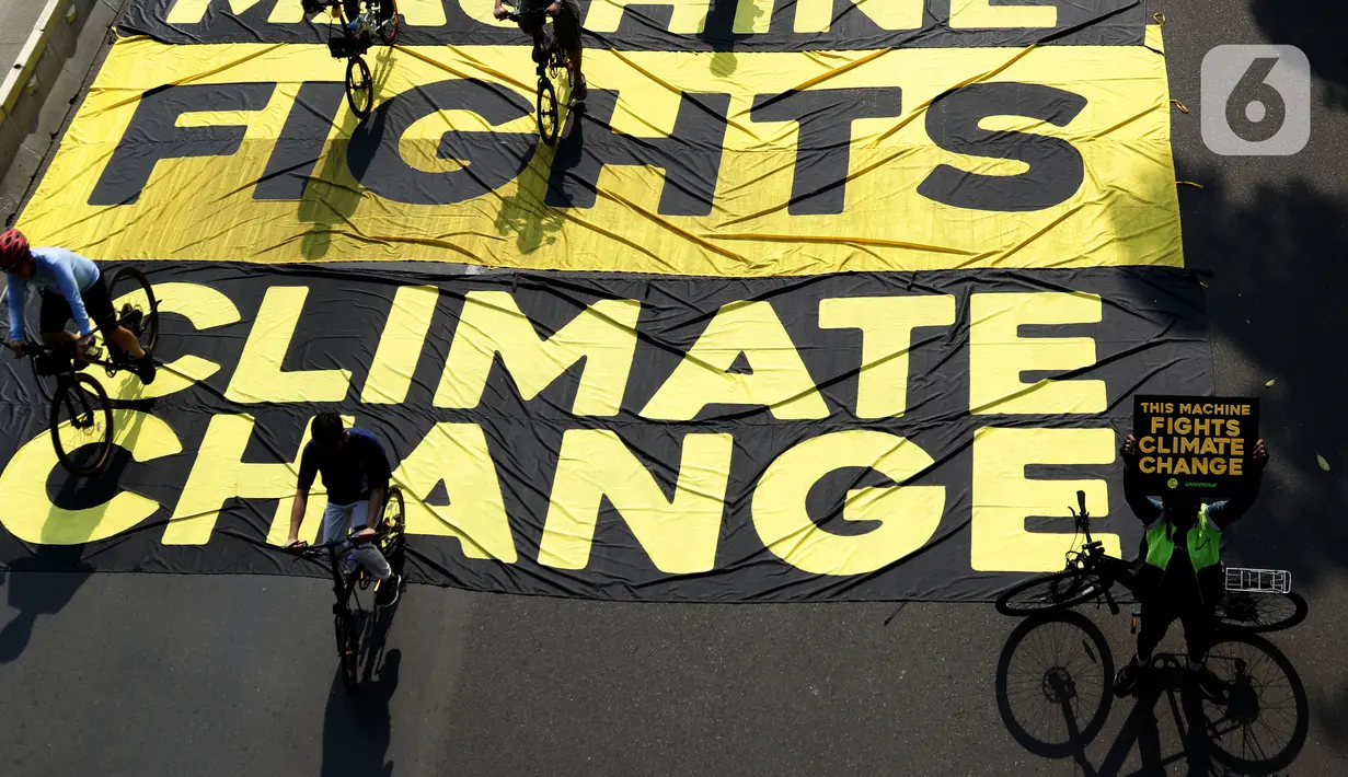 Pesepeda melintas di atas banner yang dibentangkan aktivis Greenpeace dan Bike2Work di Jalan Jenderal Sudirman, Jakarta, Minggu (5/6/2022). Aksi untuk mengkampanyekan penggunaan sepeda sebagai kendaraan ramah lingkungan dan solusi pembangunan Jakarta Kota Ramah Pesepeda. (Liputan6.com/Helmi Fithriansyah)