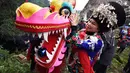 Seorang wanita mengatur posisi kepala naga dalam kegiatan rakyat bertema naga di Wilayah Otonom Etnis Miao Songtao di Kota Tongren, Provinsi Guizhou, China barat daya (24/11/2020). (Xinhua/Long Yuanbin)