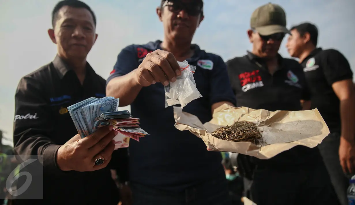 Anggota Satuan narkoba Polres Jakut memperlihatkan barang bukti narkoba serta uang yang didapatkan pada penggerebekan di Kampung Bahari, Tanjung Priok, Jakarta, Kamis (25/8). Penggerebekan melibatkan ratusan personel gabungan. (Liputan6.com/Faizal Fanani)