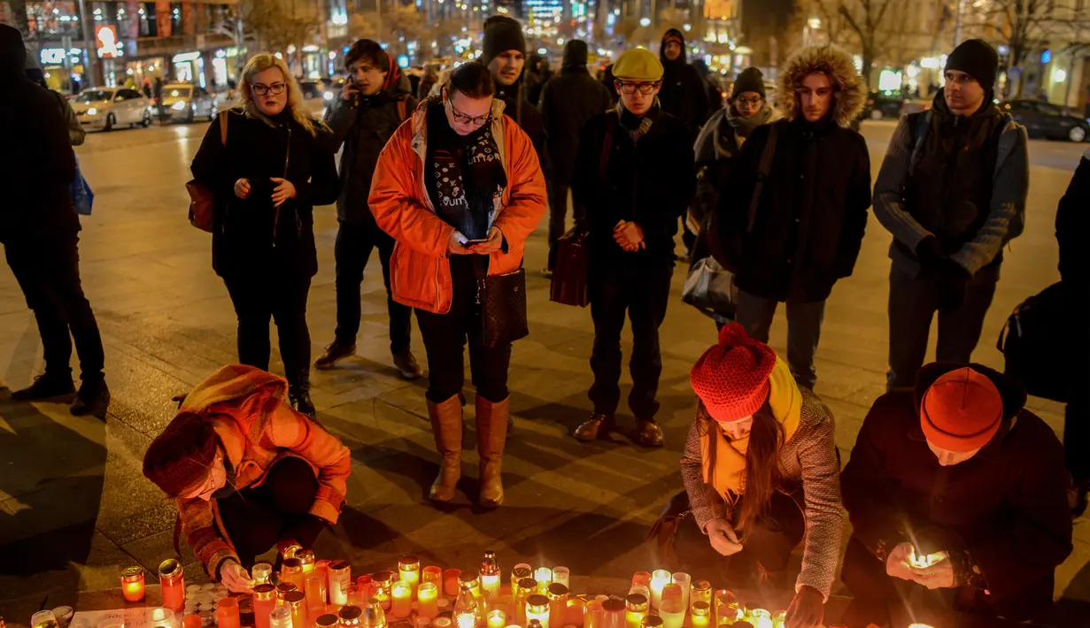 Sejumlah orang menyalakan lilin di depan foto jurnalis investigasi Slovakia Jan Kuciak di Wenceslas Square di Praha (26/2). Mereka berkumpul sambil menyalakan lilin untuk memberi penghormatan kepada Jan Kuciak. (AFP Photo/Michal Cizek)
