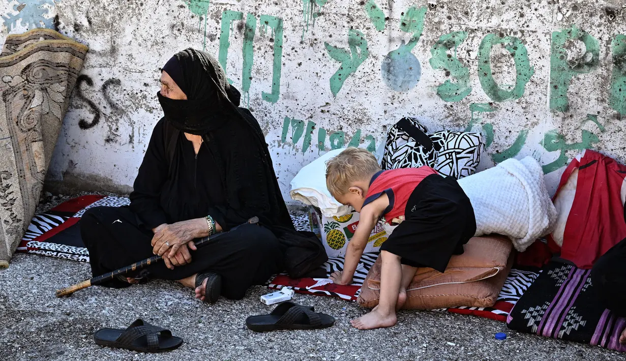 Para pengungsi terpaksa bermalam di pinggir jalan atau di tempat-tempat terbuka untuk menghindari serangan Israel. (JOSEPH EID/AFP)