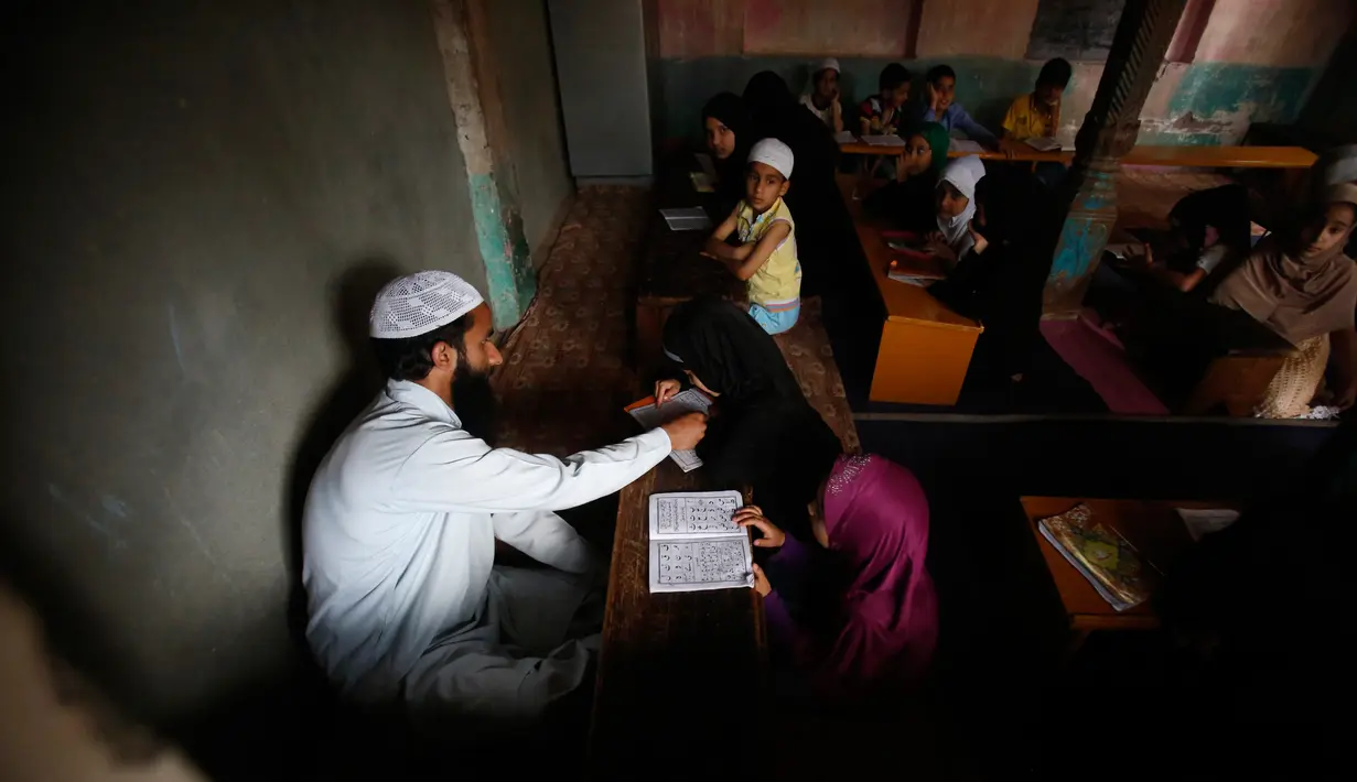 Anak-anak Kashmir saat menghadiri kelas pembacaan Al-Quran di sebuah madrasah lokal selama bulan Ramadan di Srinagar, Kashmir yang dikuasai India, (30/5). Di bulan puasa umat muslim menahan diri untuk tidak makan dan minum. (AP Photo / Mukhtar Khan)