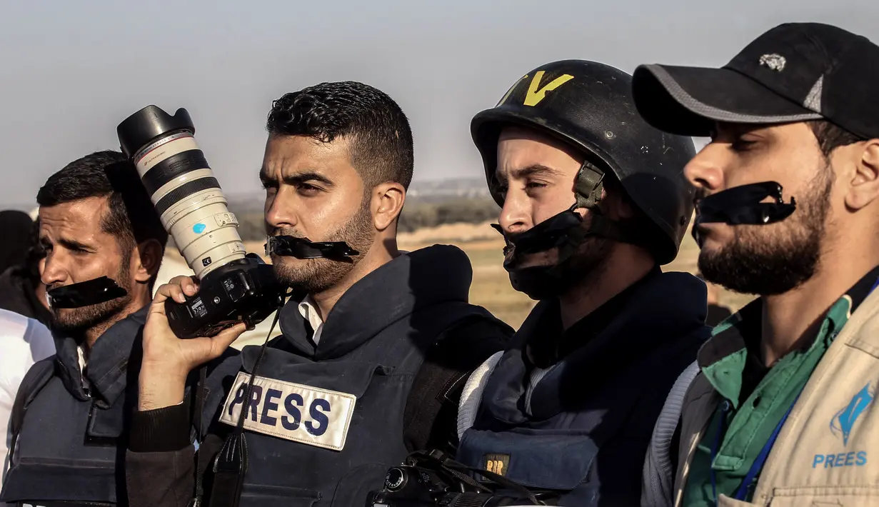 Wartawan Palestina melakban mulut mereka saat menggelar aksi protes di dekat perbatasan Israel-Gaza, Palestina (8/4). Sebelumnya wartawan Palestina Yasser Murtaja tewas dengan luka tembak saat meliput aksi protes warga Palestina. (AFP Photo/Said Khatib)