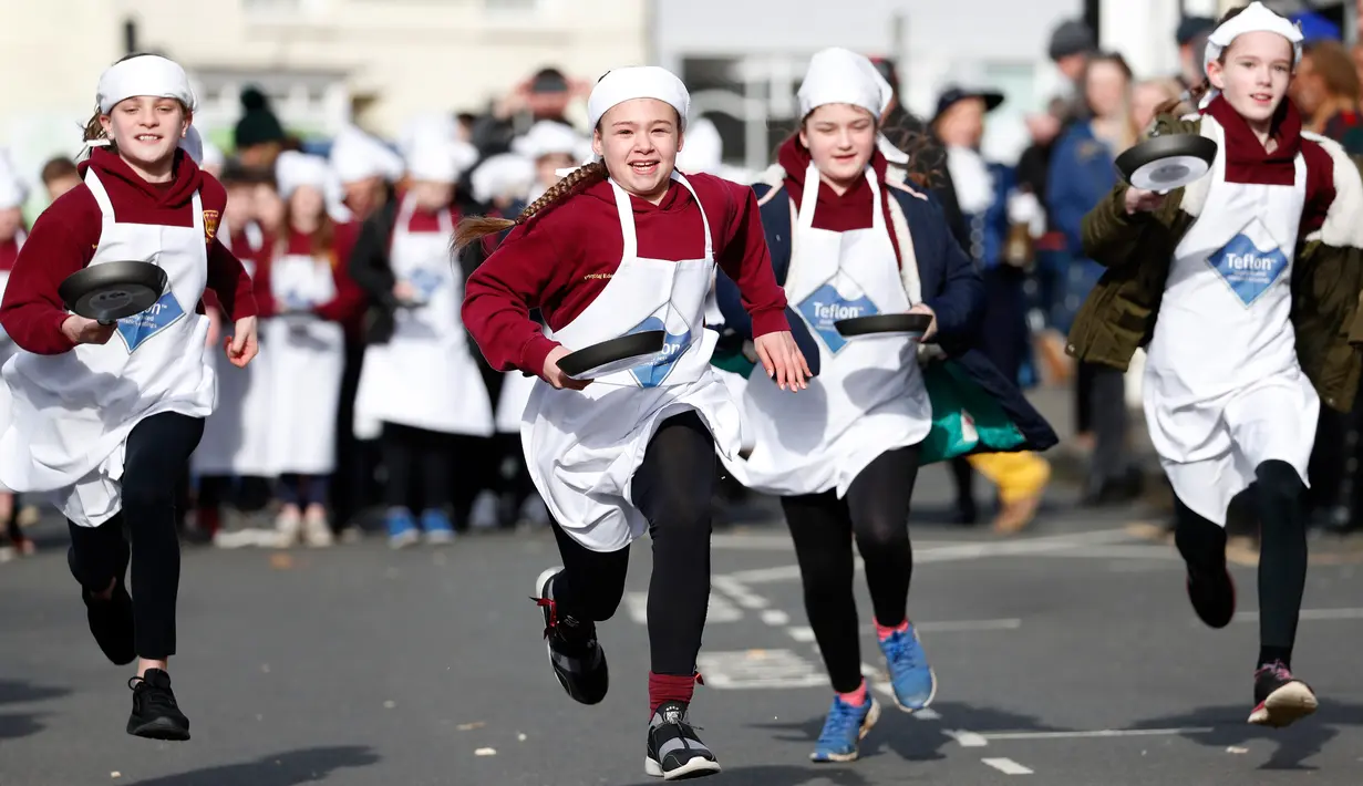 Anak-anak sekolah-sekolah lokal mengambil bagian dalam lomba lari sembari membawa wajan berisi pancake di Olney, Buckinghamshire, Inggris, Selasa (25/2/2020). Peserta kompetisi yang sudah ada sejak tahun 1445 ini harus membolak-balikan pancake sambil tetap berlari. (AP/Alastair Grant)