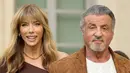 <p>Sylvester Stallone (kanan) bersama istrinya Jennifer Flavin menghadiri Ralph Lauren SS23 Runway Show di The Huntington Library, Art Collections and Botanical Gardens, San Marino, California. Amerika Serikat, 13 Oktober 2022. Jennifer Flavin memancarkan keanggunan saat dia menyelipkan bingkai rampingnya ke dalam gaun one-shoulder cokelat yang mengalir ke lantai. (Amy Sussman/Getty Images/AFP)</p>