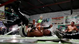 Pegulat yang dikenal sebagai Gio Malkriado menyerang lawannya, Ciclope dengan menggunakan lampu tabung panjang saat pertandingan gulat di Arena Neza di pinggiran Mexico City, Meksiko (28/10). (Reuters/ Carlos Jasso)