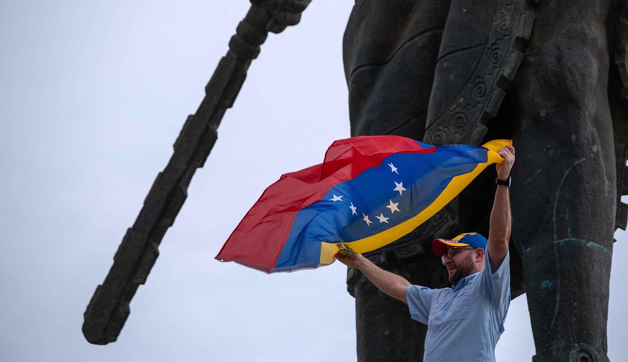 Menurut data Organisasi Internasional untuk Migrasi Perserikatan Bangsa Bangsa (PBB), sekitar 7,7 juta warga Venezuela telah meninggalkan negara itu sejak 2014. Tampak dalam foto, seorang warga Venezuela yang tinggal di Meksiko mengibarkan bendera nasional saat merayakan penangkapan pemimpin mereka, Nicolas Maduro, di monumen Cuauhtemoc, Tijuana, pada 3 Januari 2026. (Guillermo Arias/AFP)