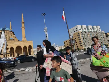 Orang-orang yang melarikan diri dari pengeboman Israel di pinggiran selatan Beirut, berkumpul dengan barang-barang mereka di Martyrs Square di pusat ibu kota Lebanon di mana mereka bermalam pada 28 September 2024. (JOSEPH EID/AFP)
