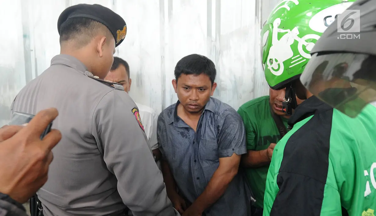 Polisi dan sejumlah pengemudi ojek online menginterogasi terduga copet sebelum dibawa menuju Mapolda Metro Jaya di Jalan Jenderal Sudirman, Jakarta (2/4). (Merdeka.com/Arie Basuki)