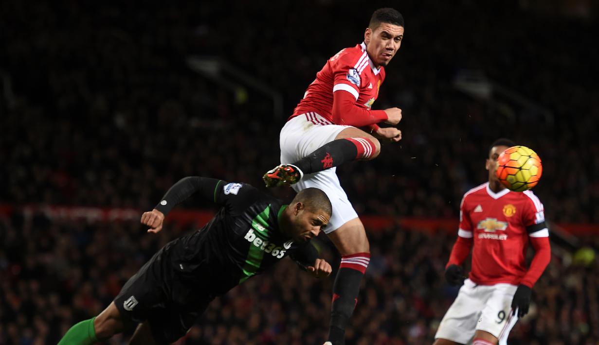 Pemain Manchester United, Chris Smalling, berduel dengan pemain Stoke City, Glen Johnson, dalam lanjutan Liga Inggris di Stadion Old Trafford, Manchester, Rabu (3/2/2016) dini hari WIB. (AFP/Paul Ellis)